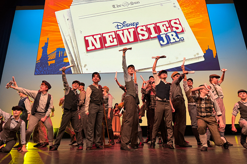 Newsies JR logo with children in pose holding newspapers in defiance