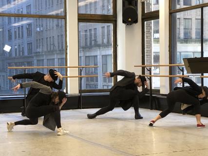 A group of dancers wearing black hats and black outfits performing a move.