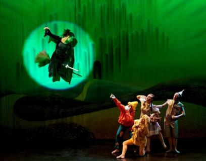 A woman flying on a broomstick scaring a group of people.